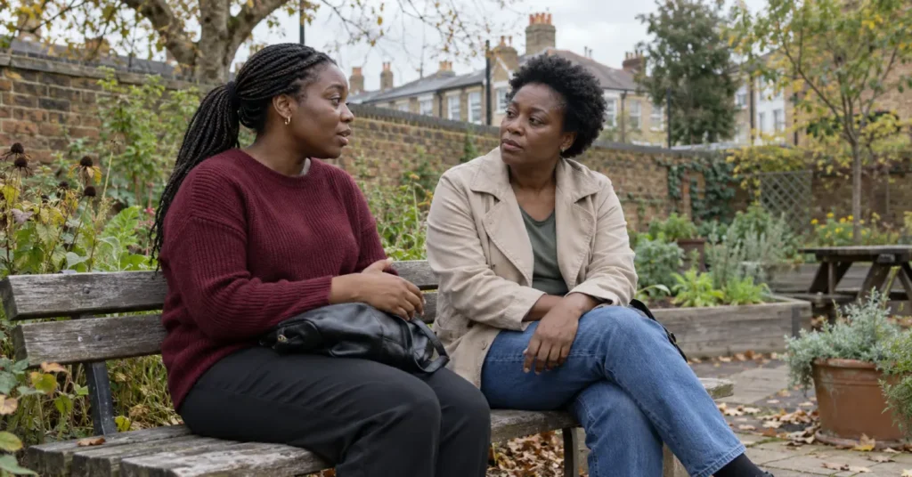 Two women talking while sitting on a wooden bench in a garden.
